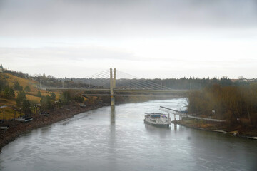 Edmonton, AB, CND – Apr 27, 2025: Boat moored along the North Saskatchewan River near a modern...