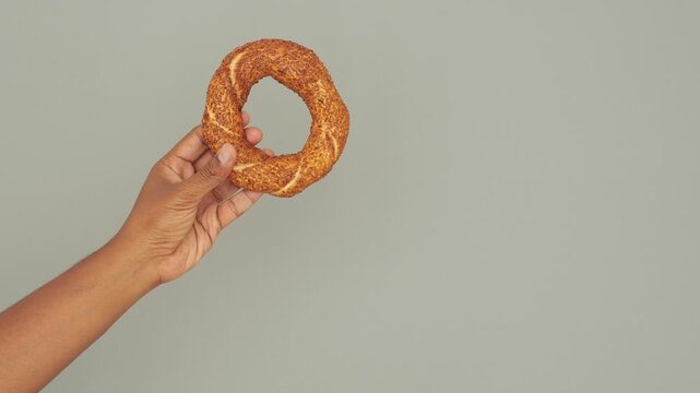 Delicious fresh bagel held by a hand in the kitchen
