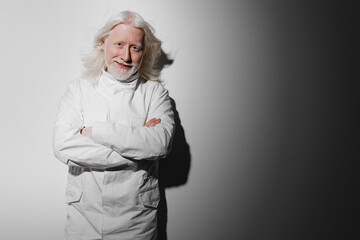 Portrait of a smiling elderly man in a white lab coat, standing confidently against a soft gray gradient background, showcasing professionalism and expertise, ideal for medical, scientific, or