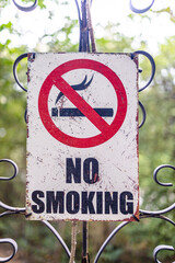 Old scratched no smoking sign in outdoor area, symbol of health regulation and public awareness for smoke-free zone