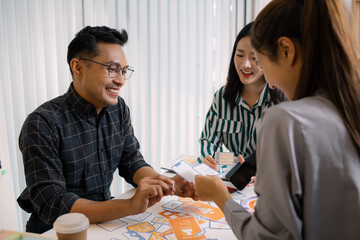 A group of UX/UI designers brainstorming creative ideas together, discussing color palettes and layout concepts for a new mobile application interface in a modern design office.