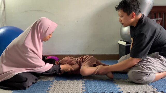 Parents are helping their children perform patterning therapy exercises at home, supporting physical development, coordination, and family bonding in a warm and caring atmosphere.