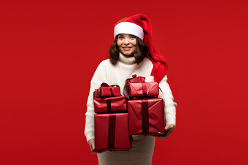 Woman in Santa hat holding multiple Christmas gift boxes.