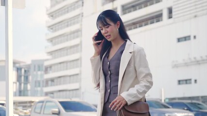 Young business businesswoman walking outdoor passing sleek modern office buildings on busy urban street, checking time on wrist holding phone focused for travel. - Powered by Adobe