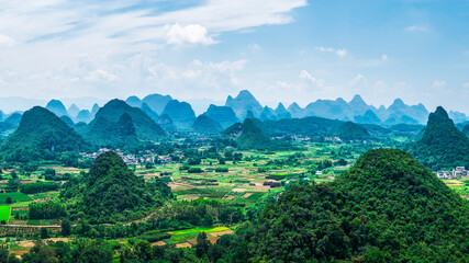 Breathtaking aerial view of the lush green karst mountain landscape and rural valley under a blue sky in Guilin.