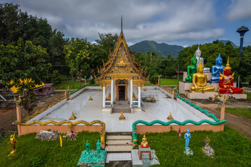 Obraz premium A breathtaking drone view of Wat Hat Ngio Rai surrounded by lush forests and mountains in Sai Yok District, Kanchanaburi, Thailand.