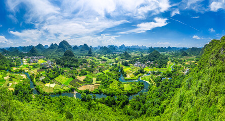 Meandering river flowing through a vast green valley surrounded by countless karst mountains in Guilin.
