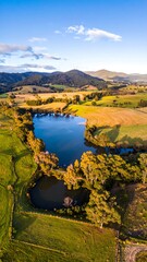 Fototapeta premium Aerial view of a scenic landscape with a lake surrounded by fields