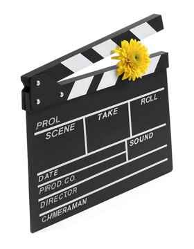 A black clapperboard, with white stripes on the clapstick, is partially open, and a bright yellow flower is placed in the opening