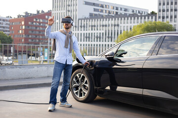 A man wearing a VR headset charges his electric vehicle, seemingly interacting with a virtual interface.