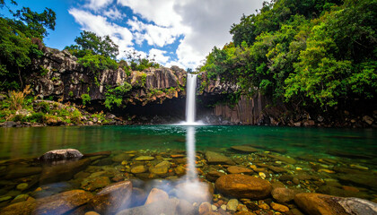 Stunning Waterfall in Lush Tropical Landscape with Clear Emerald Pool and Rocky Surroundings.