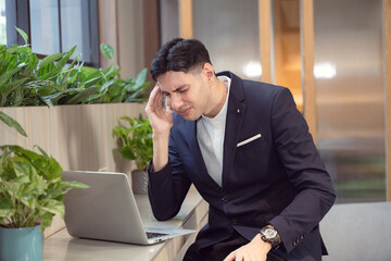 Stress, depression and business man on laptop in office with burnout, taxes or bad news of bankruptcy email. Headache, migraine and professional with fatigue, anxiety or sick of financial crisis debt.