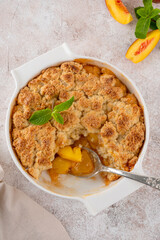 Homemade summer peach cobbler. Pie with juicy peaches, a scoop of vanilla ice cream and fresh mint on a white plate. Comfort food.