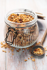 Granola breakfast cereal in glass jar with spoon