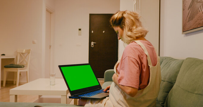 Side view expectant mother working computer with green screen at home. Pregnant studying on computer with green screen at home.