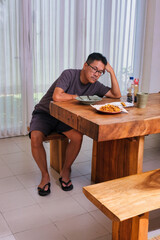 Man sitting in dining table, losing appetite to eat