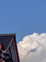 Roof and cloud against clear blue sky
