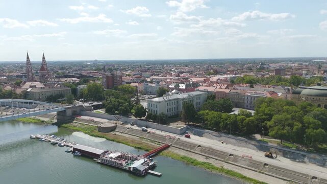 Scenic drone flight above the Tisza River, capturing Szeged&rsquo;s Ferenc M&oacute;ra Museum and tranquil riverside atmosphere.