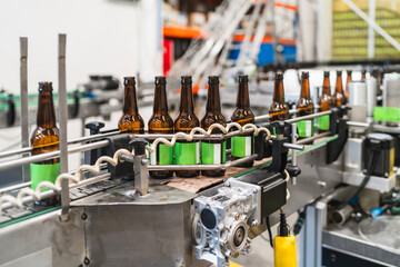 Beer bottles with green labels traveling on a conveyor belt in a modern brewery, depicting industrial production and bottling