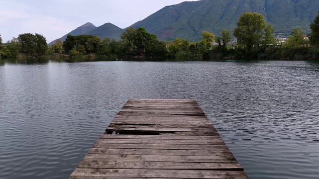 Old wooden dock at Lake Telese, Italy, filmed in summer light with calm water and scenic motion.