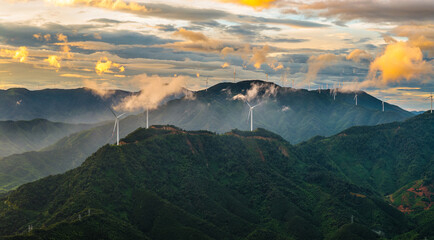 Wind turbines on the green mountain generating sustainable electricity under a dramatic sunrise sky © ABCDstock