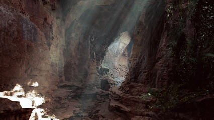Sunlight streams into a serene cave, casting beautiful rays against the rugged stone walls. Lush green plants peek through, enhancing the tranquil, mystical atmosphere of the underground space.