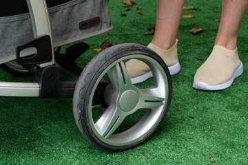 Fototapeta premium Mom with a baby in a stroller walks in the park on green grass