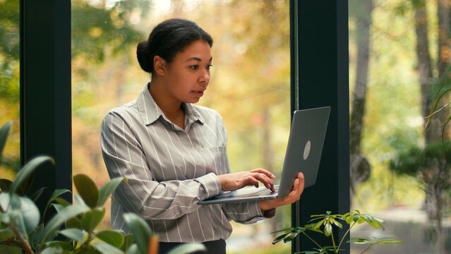Happy, Hispanic Business Woman Working on Laptop Computer with Motivation, Success at Office. Excited, Employee, Lawyer, Female Businesswoman Corporate Job. Greenhouse Background