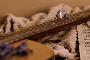 Audiology hearing aid on guitar strings symbolizes the blend of music and hearing solutions for deeper connection