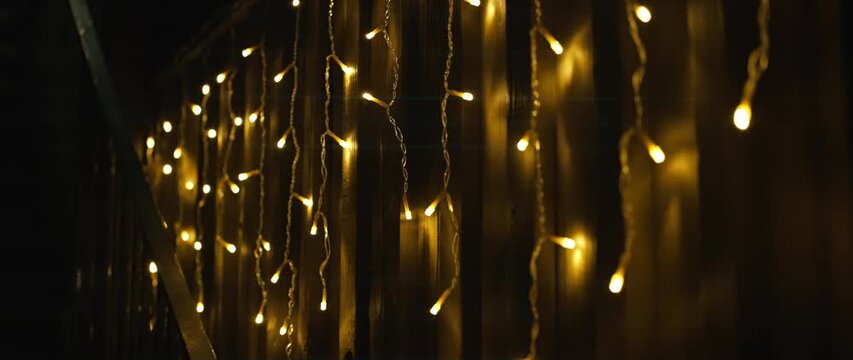 Warm string lights hanging on wooden fence at night