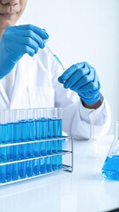 Scientist in lab coat using pipette with test tubes filled with blue liquid
