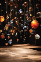 Numerous translucent spheres of varying sizes and colors hang from above, illuminating a dark, wooden stage below.  They create a celestial, ethereal atmosphere