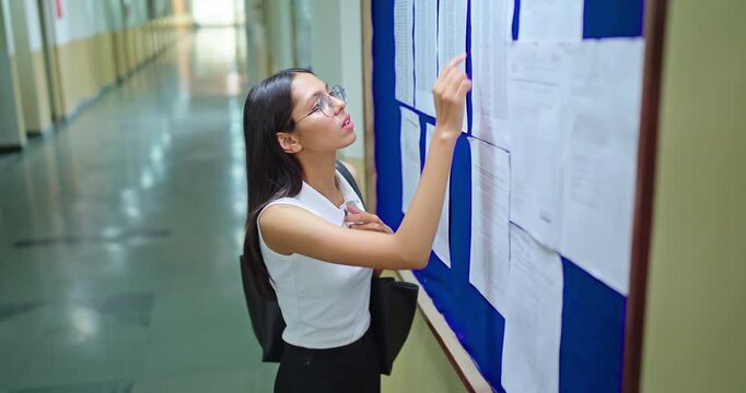 Indian young adult gen z female lady look notice board do check results fail in exam report feel bad campus area. Stress teen pupil girl wear bag read new paper list name data study time college place