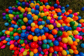 A vibrant pile of colorful plastic balls on the grass, typically used for kids’ play or event decorations. Bright, cheerful, and eye-catching.