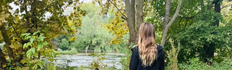 Back View of Blonde Woman Standing by a River in Peaceful Nature