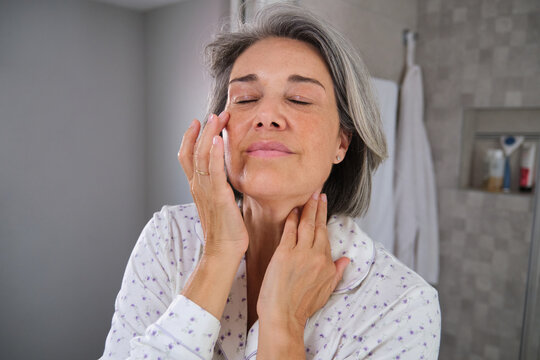 Woman enjoying morning skincare and self-care routine in bathroom - Powered by Adobe