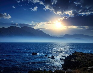 Ocean coast mountains silhouetted under bright, sunlit clouds