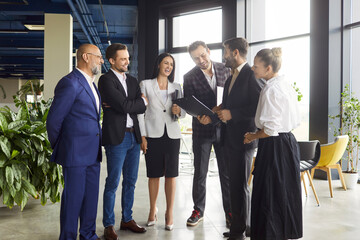 Discussion of business team meeting in modern office hall. Informal conversation of colleagues in lobby about business documents, corporate strategy and collaboration, success of agreement