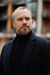 Bearded man in turtleneck and coat outdoors