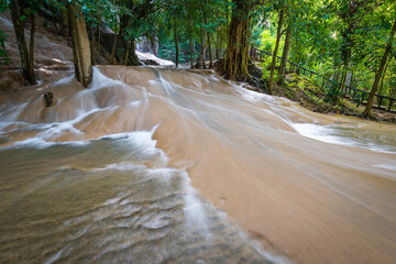Sai Yok Noi Waterfall in Kanchanaburi, Thailand, is a charming spot surrounded by lush forest, a gentle cascade, peaceful nature, and beautiful scenery.
