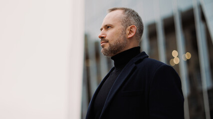 Portrait of adult man in coat standing on urban street 