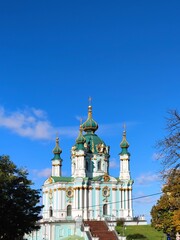 A masterpiece of Elizabethan Baroque by Rastrelli. The magnificent St. Andrew's Church in Kyiv with its turquoise facade and golden domes against a clear blue sky.