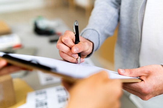 Female customer signing on document after receiving package in warehouse