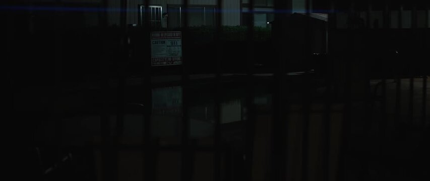 Night swimming pool behind fence with warning sign and water reflection