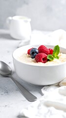 A healthy breakfast of porridge, berries, and mint leaves with cream