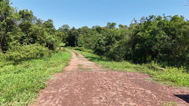 Entrance gate to private residence in Misiones, Argentina, with metal and wood design opening to a stone path into lush forest,l transitioning from architecture to subtropical nature, low drone glide