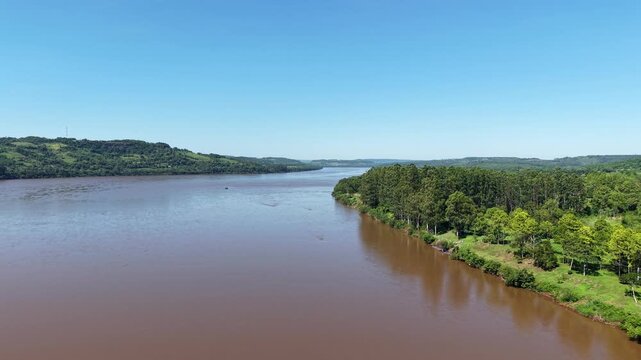 Drone view over Uruguay River near Panamb&iacute;, Misiones, Argentina, showing pine and eucalyptus plantations, native forest, with biodiverse subtropical landscape shaped by forestry and conservation.