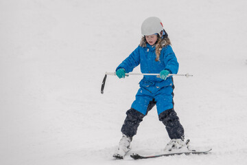 Child learning to ski during a snowfall in the mountains. A winter sports scene capturing the joy...