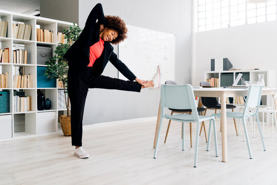 Businesswoman doing stretching exercise at desk in office