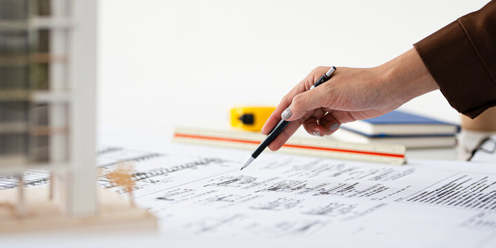 Close up hand of Architect or engineer professional holding pen working on blueprint , structural floor plans, triangular scale , Shop drawing , calculator, laptop and engineering tools.